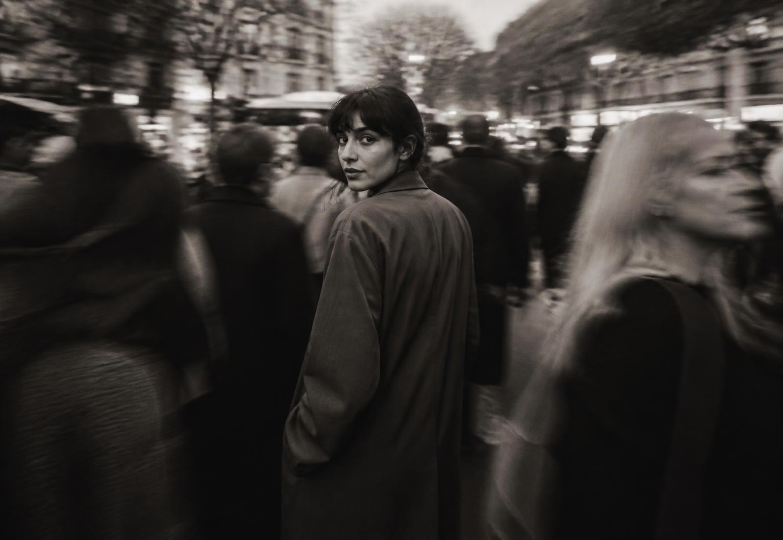 A person turning to look back through a moving crowd