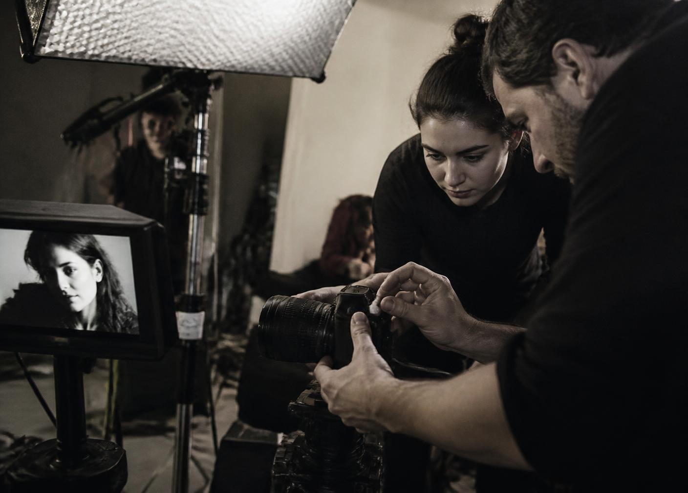 Behind the scenes of a photo shoot, hands adjusting a camera